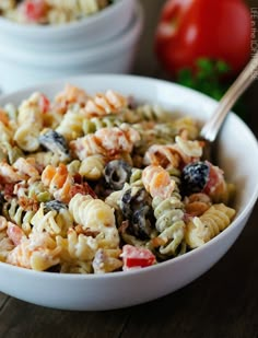 a white bowl filled with pasta salad on top of a wooden table