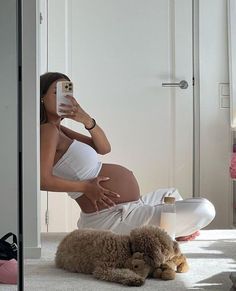 a pregnant woman taking a selfie with her cell phone while laying on the floor