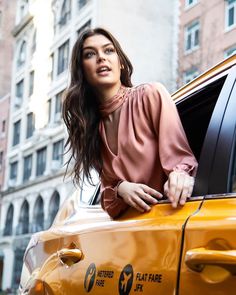 a woman leaning out the window of a taxi cab