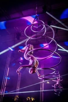 two people are performing aerial acrobatic tricks in front of purple lights at an event