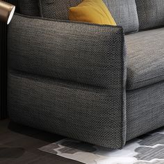 a gray couch sitting on top of a hard wood floor next to a lamp and rug