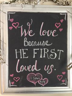 we love because he first loved us handwritten chalkboard sign with hearts on it