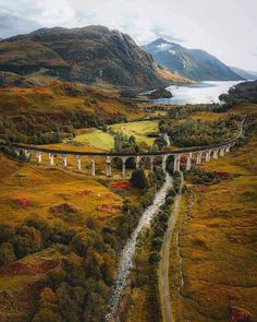 an aerial view of a bridge over a river in the middle of a green valley