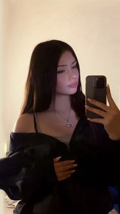 a woman taking a selfie with her cell phone in front of her face and wearing a black top