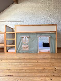 bunk beds with curtains on them in a loft style room, next to a white brick wall and wooden floor