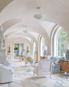 a living room filled with white furniture and lots of windows