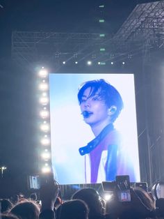 a person standing on top of a stage holding a cell phone in front of him