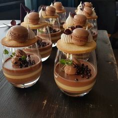 desserts are arranged in wine glasses on a table