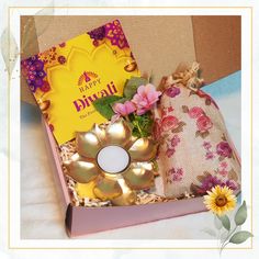 a gift box with flowers, candles and a card in it that says happy diwali