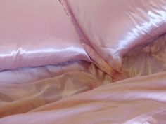 a bed with pink sheets and pillows on it