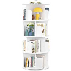 a white book shelf filled with books on top of a white floor next to a yellow vase