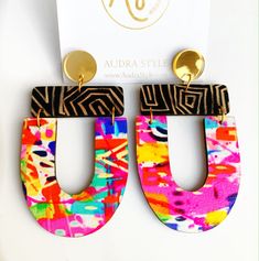 the colorful earrings are on display in front of a white card and gold earring