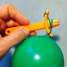 a person is holding an orange handled balloon with one hand and the other hand on top of it