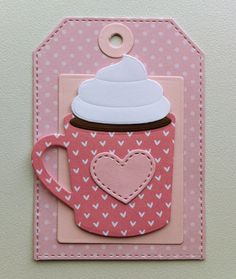 a pink card with a coffee cup and heart cutout on the front, hanging from a hook