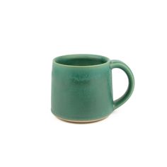 a green mug sitting on top of a white table