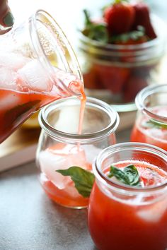 someone is pouring water into some glasses with strawberries in them