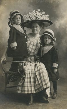 an old black and white photo of three children in dresses with hats on their heads