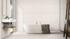 a white bath tub sitting under a window next to a wooden shelf filled with towels