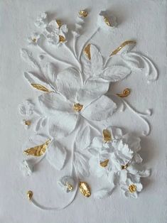 a white and gold flower with leaves on the bottom is shown in this image, it appears to be made out of paper