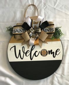 a welcome sign hanging from the side of a white tablecloth covered wall with burlocks and bows