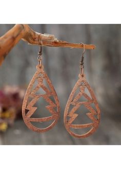 the copper earrings are hanging from a branch with leaves on it and one earring has an intricate design