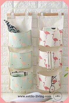 three pockets hanging from the wall with flamingos on them and one pocket for pens