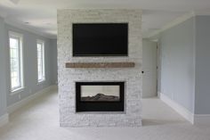 an empty living room with a fireplace and flat screen tv