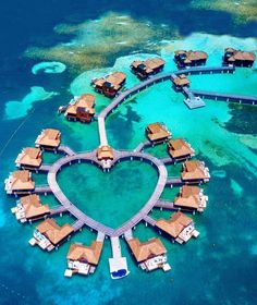 an aerial view of a heart - shaped island in the middle of the ocean with overwater huts