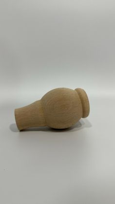 a small wooden object on a white surface with a shadow from the top to the bottom