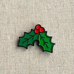 a pin with holly leaves and berries on it