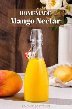 homemade mango nectar drink in a glass bottle next to two peaches on a table