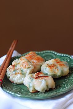 some dumplings are on a green plate with chopsticks