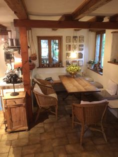 a dining room table and chairs in front of an open kitchen area with wooden beams