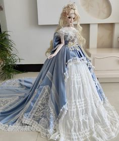 a doll is dressed in a blue and white dress