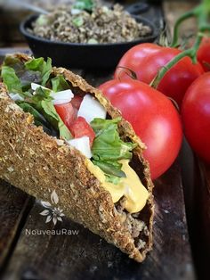 an open pita sandwich with tomatoes and lettuce on it next to other food