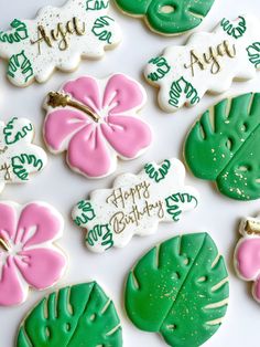 decorated cookies with flowers and leaves are arranged on a white tablecloth that says happy birthday