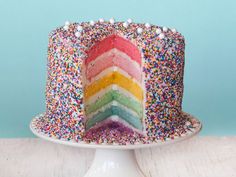 a multi - colored cake with sprinkles on top sits on a plate