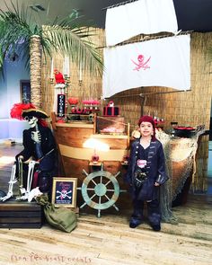 a child standing in front of a fake pirate ship and other items that are on display