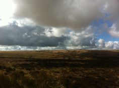 the sky is filled with clouds over an open field and grassy area in the foreground