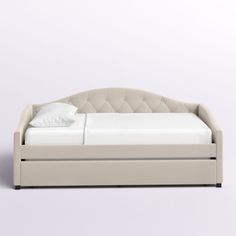 a white bed sitting on top of a white floor next to a pillow and blanket