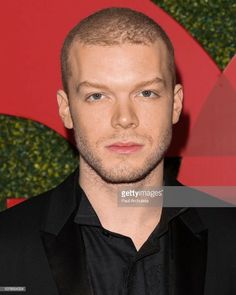 a man in a black shirt and suit posing for the camera