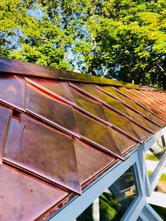 the roof of a building with metal shingles and trees in the backround