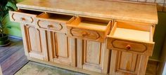 an old fashioned wooden cabinet sitting on top of a floor next to a potted plant