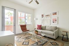 a living room filled with furniture and pictures hanging on the wall above a glass coffee table