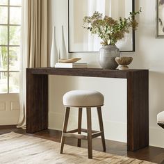 a table with stools and vases on it in front of a wall mirror