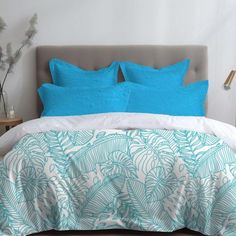 a bed with blue and white pillows on top of it next to a night stand