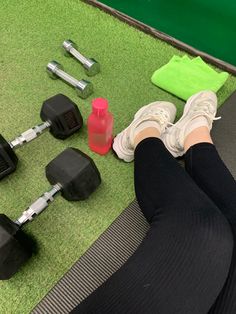 a person sitting on the ground with their feet propped up next to dumbbells