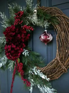 a christmas wreath on the front door with an ornament