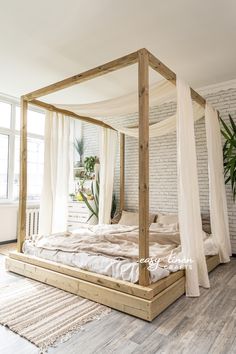 a bed with white sheets and curtains in a room next to a brick wall that has a potted plant on it