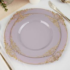 two purple plates sitting on top of a table next to utensils and silverware